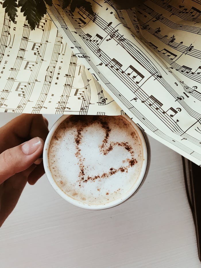A cup of cappuccino with heart latte art on a background of musical notes.