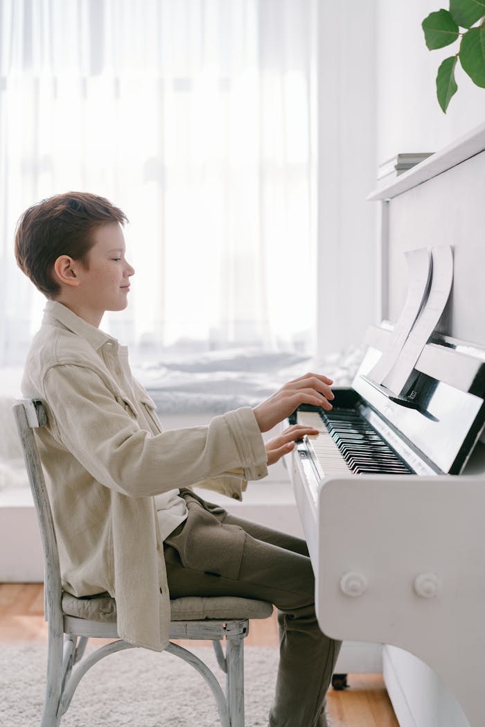 Young boy skillfully playing piano indoors, showcasing talent and concentration.